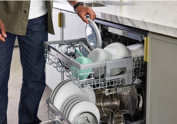 A person grabbing a dish from an LG dishwasher 