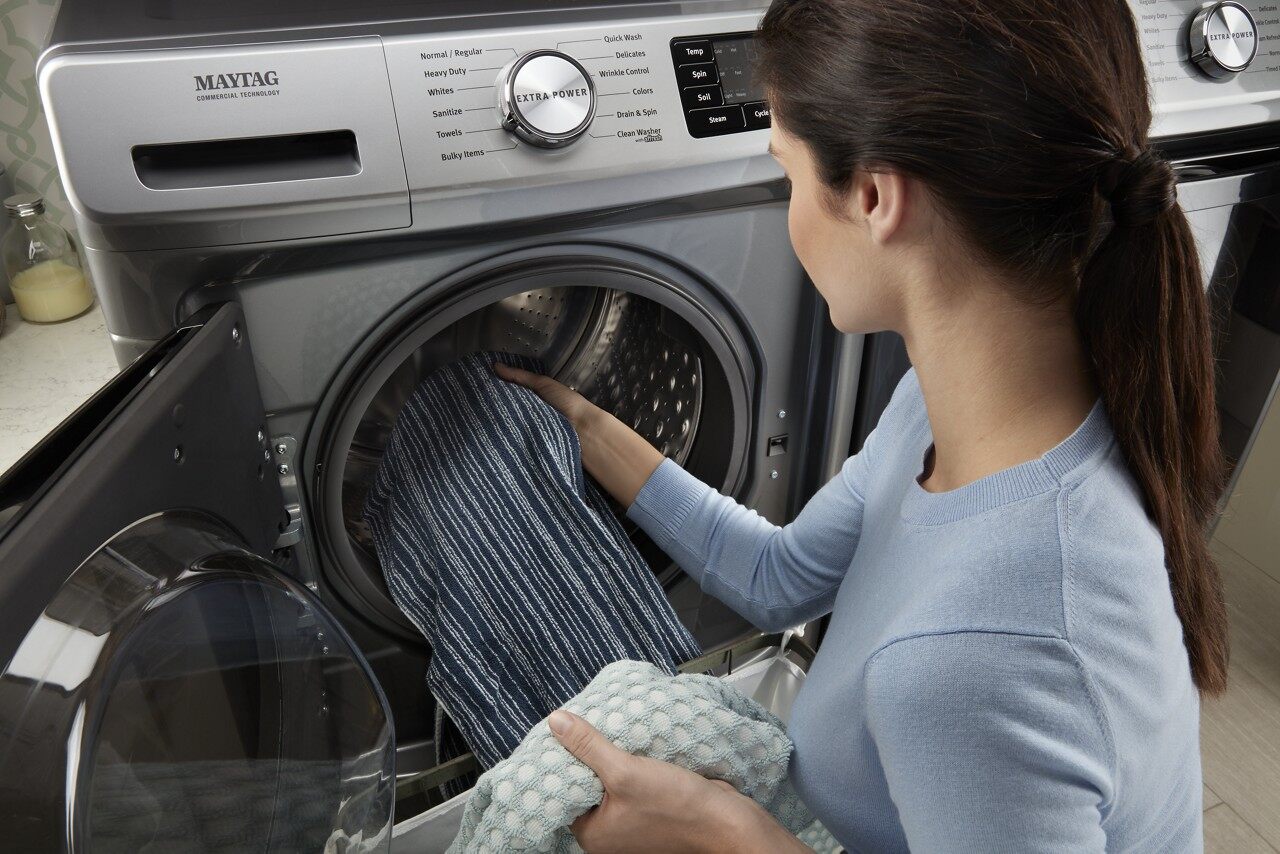 A woman putting clothes into the Maytag mhw6630hc front load washer 