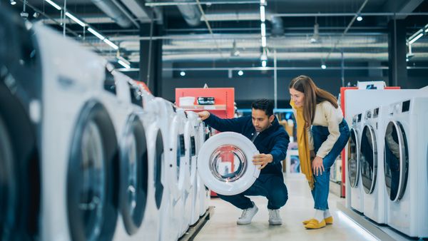 A couple inspecting a front load washer in a store 