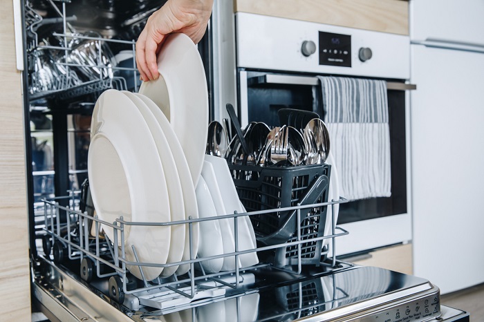Open dishwasher with clean glasses and dishes close-up after washing.