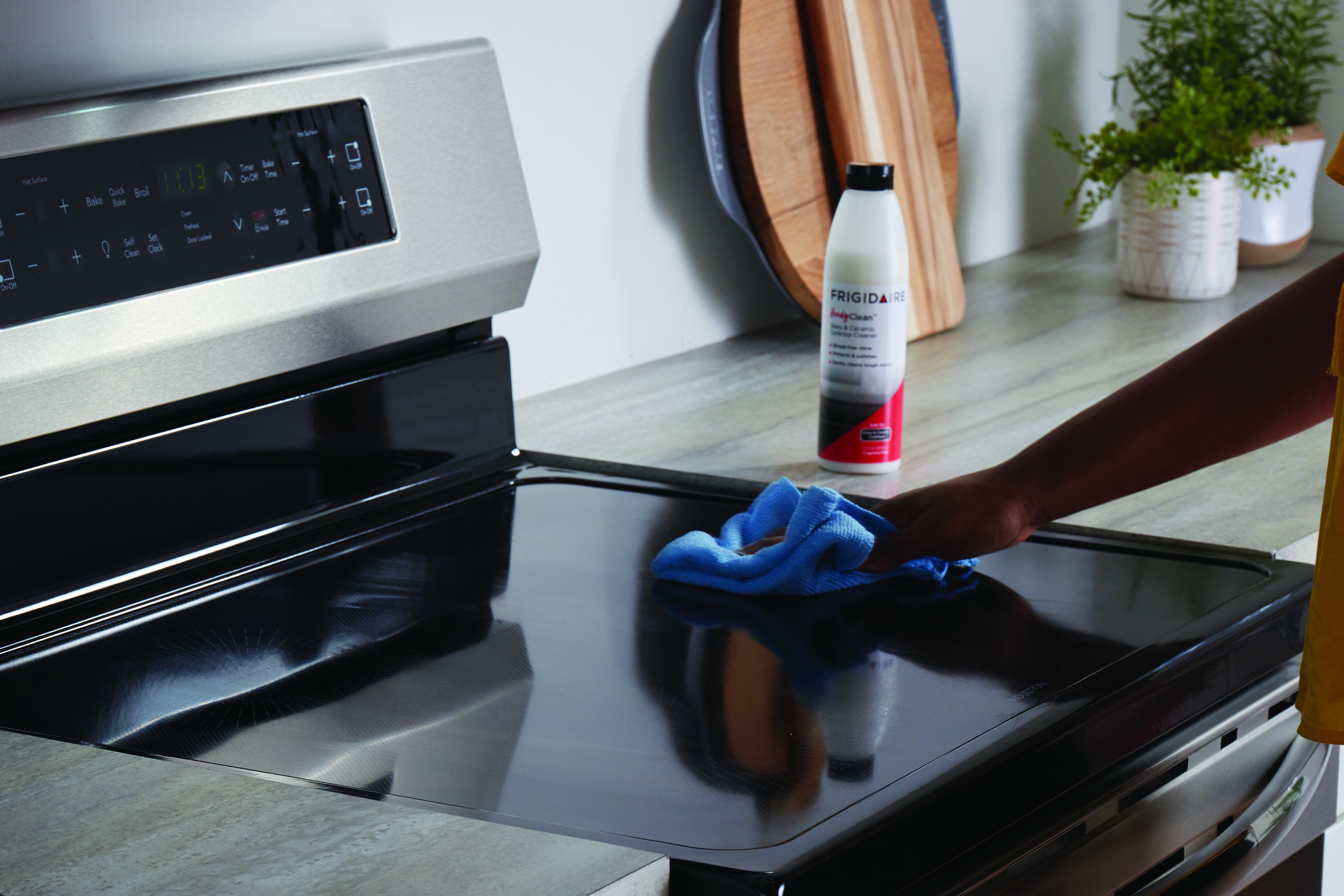 female hand wipes surface of smoothtop range with cleaner and a microfiber cloth