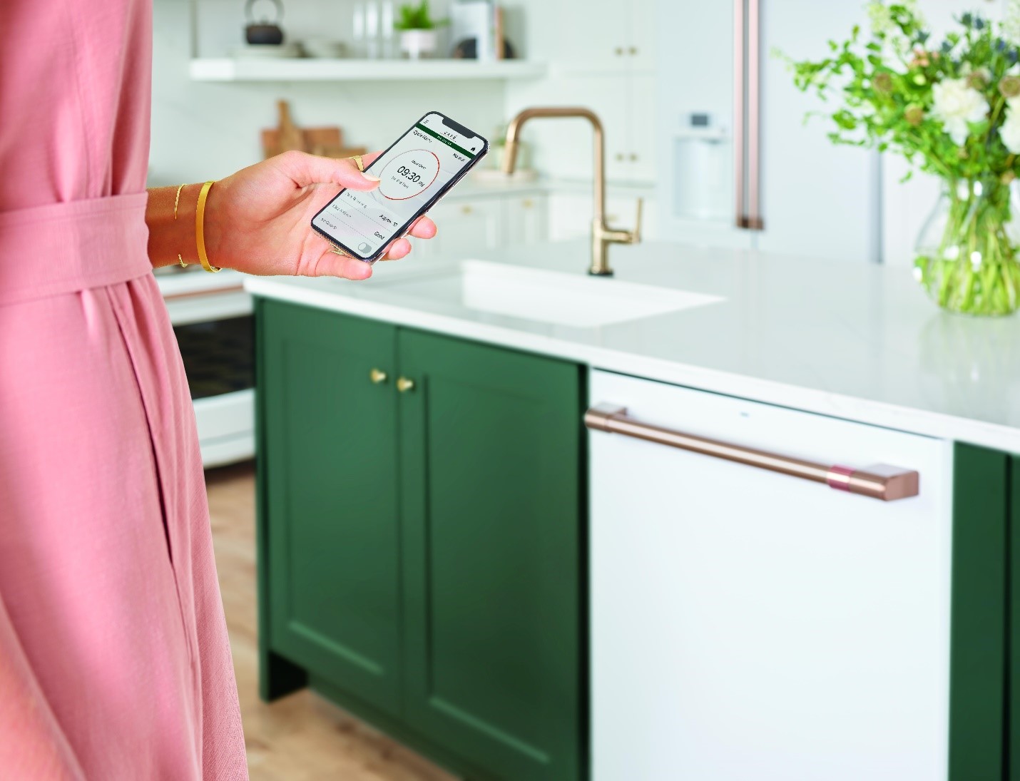 woman uses smartphone to monitor her Cafe built in dishwasher