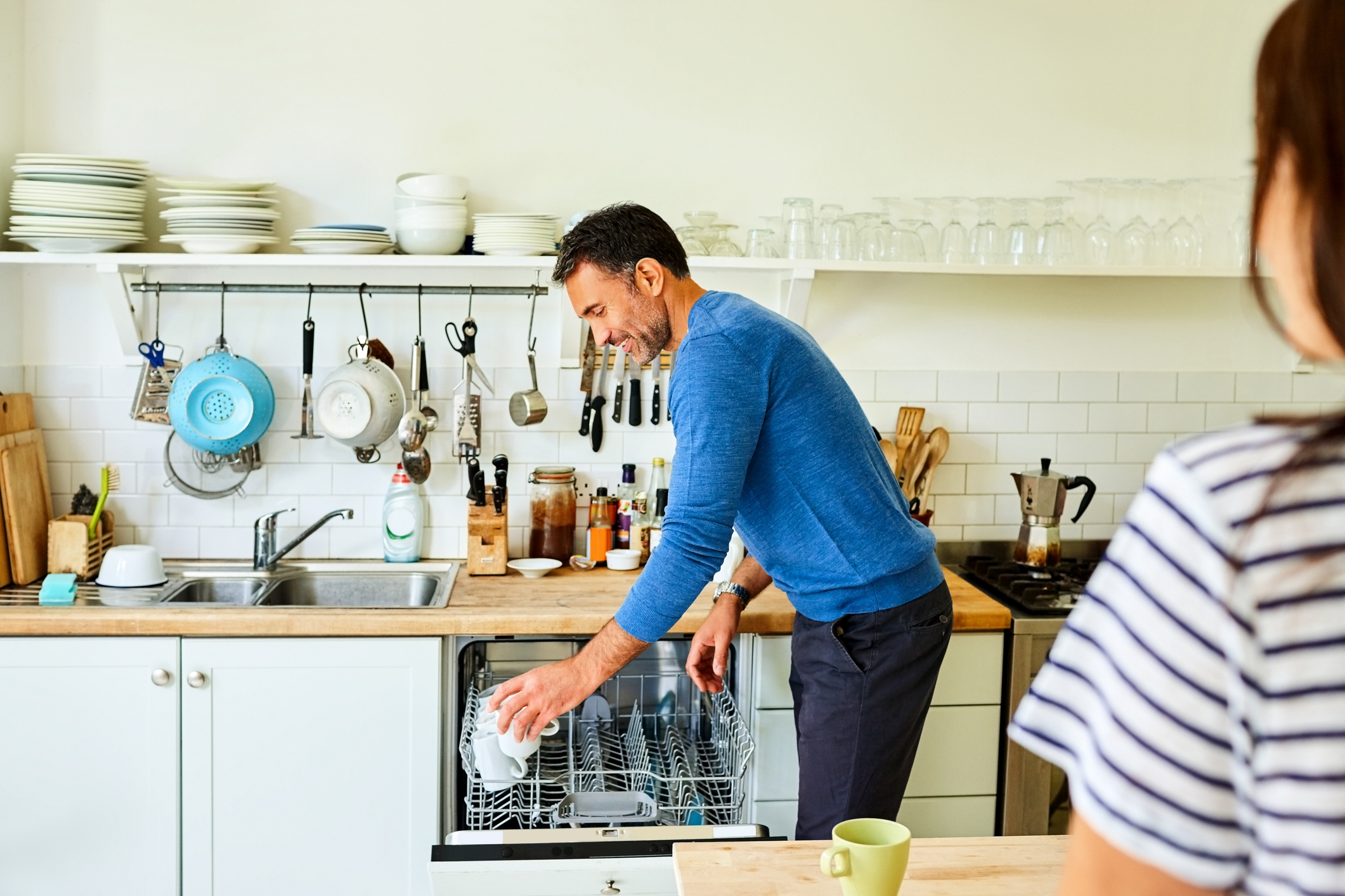  man loading coffee mugs into the dishwasher