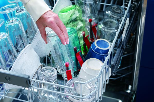 A person using the bottle holders on a GE dishwasher