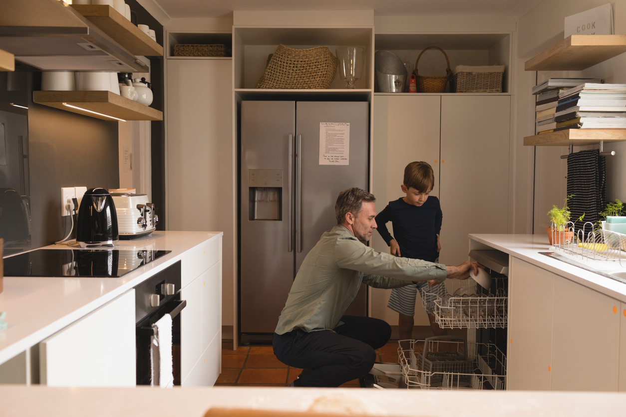 Father and son load dishes into a dishwasher 