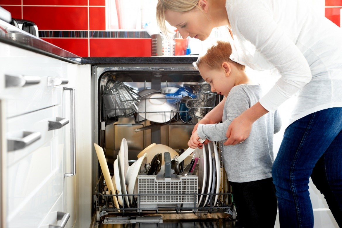 Woman and child loading dishes into a built-in dishwasher