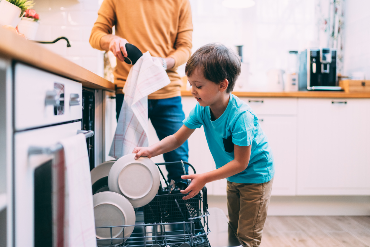 father and young son emptying dishwasher together
