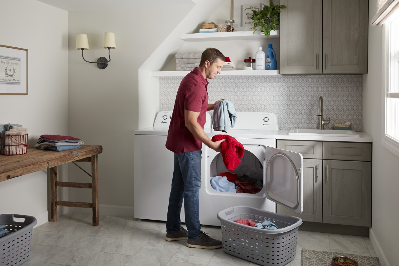 A man taking clothes out of an Amana dryer 