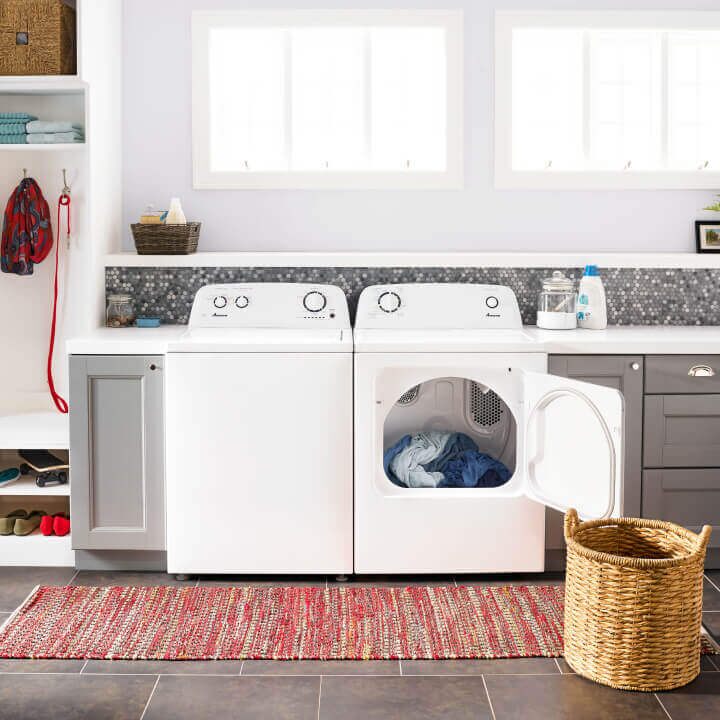 A top load Amana washer and dryer with a laundry basket 