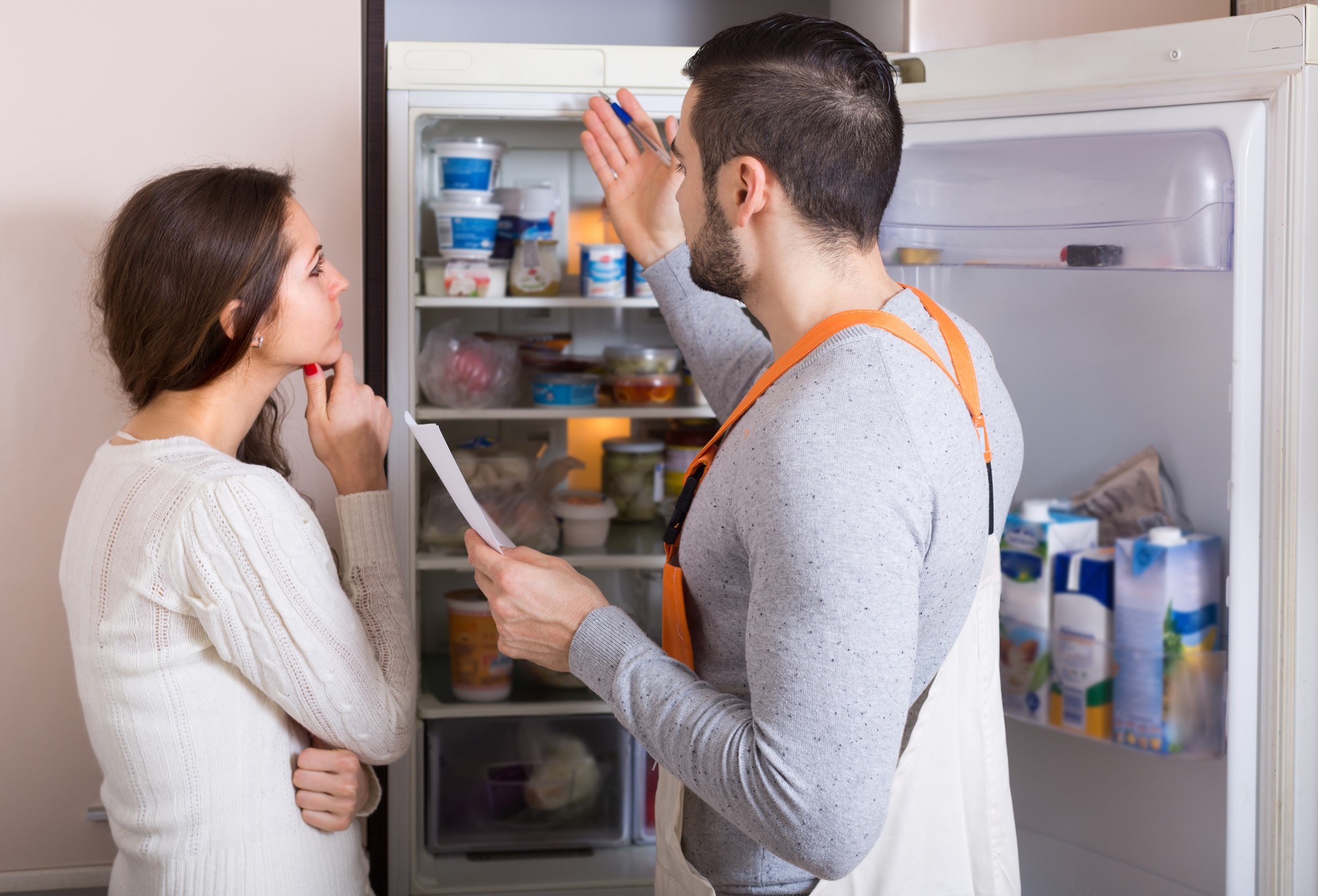 An appliance technician explaining a repair to a woman 