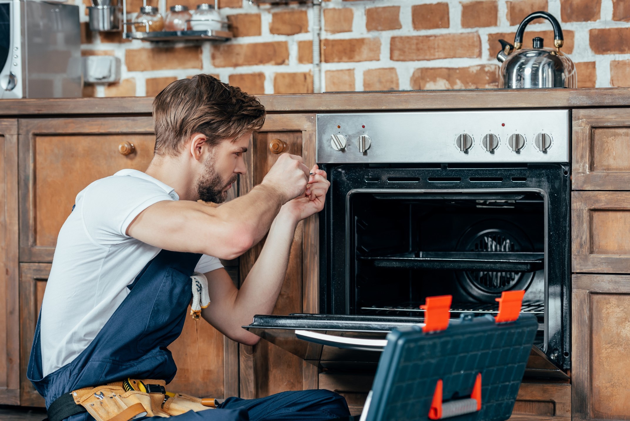 A repair man fixing an oven 