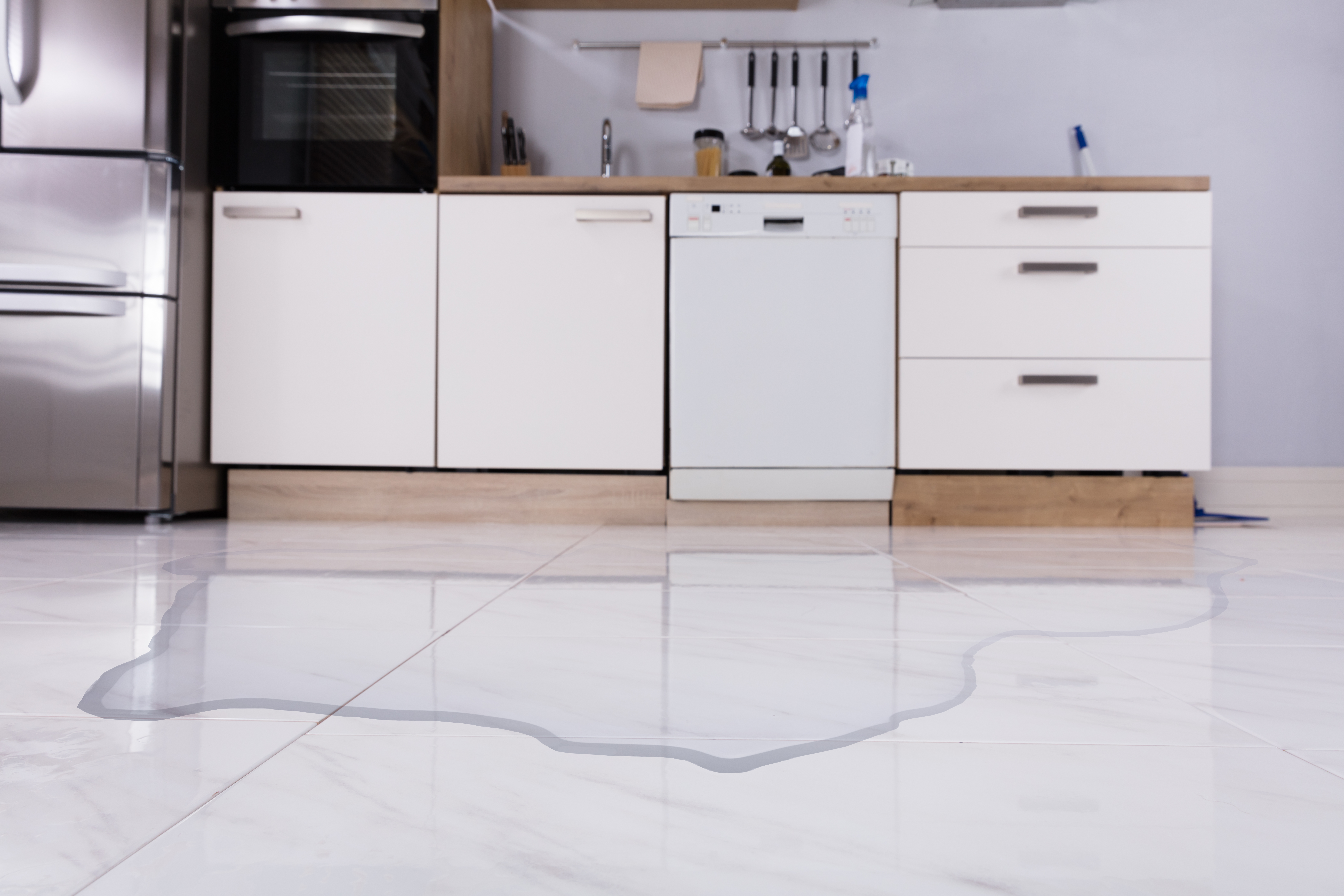 Wide shot of a dishwasher leaking water on the floor 