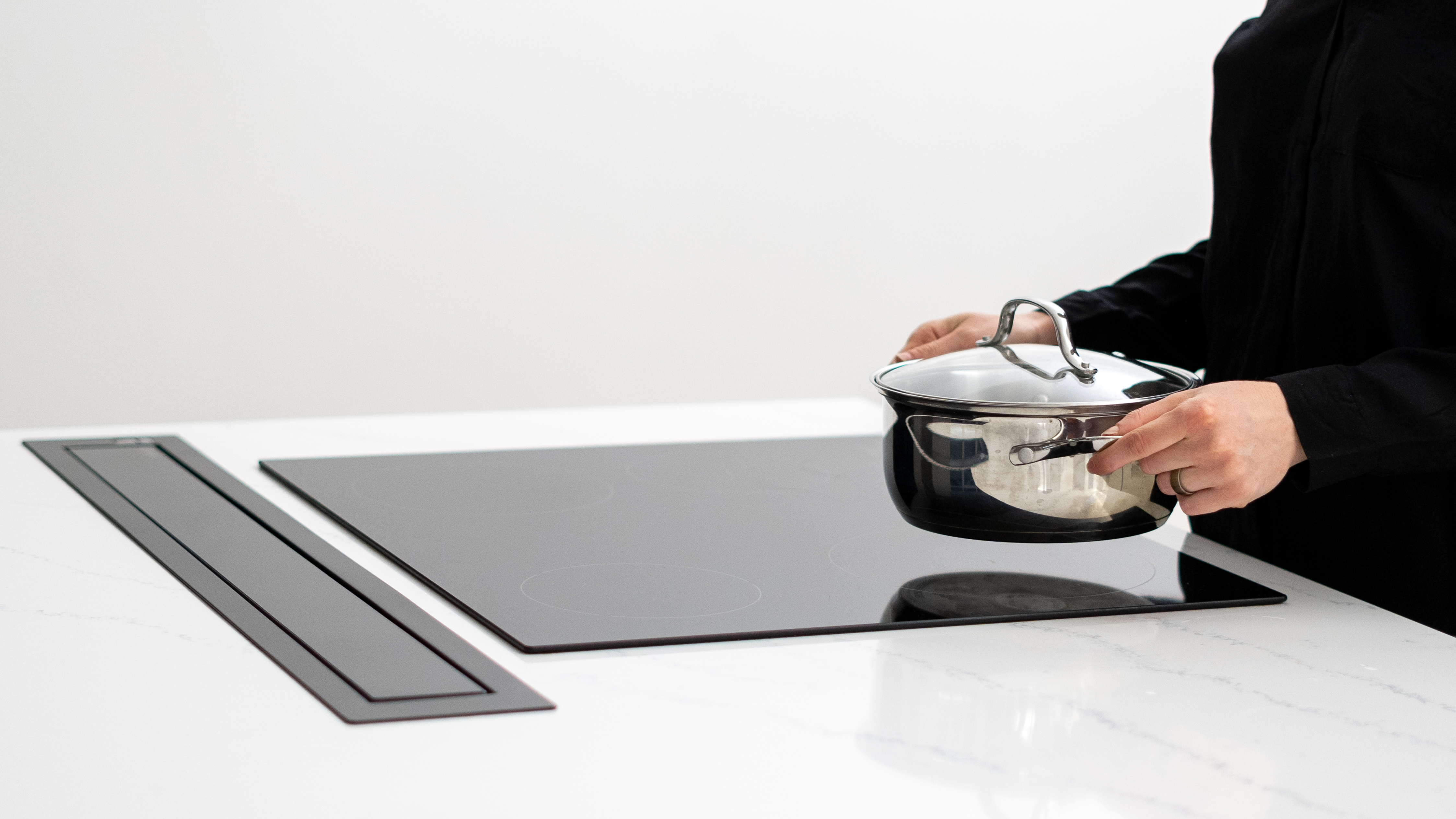 A person placing a pot onto an induction cooktop 
