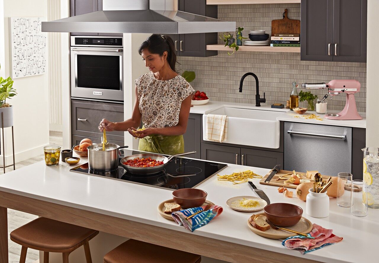 A woman cooking on top of a KitchenAid induction cooktop 