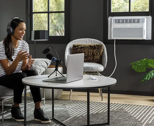 A woman enjoys a cooling air conditioner unit in her modern living room