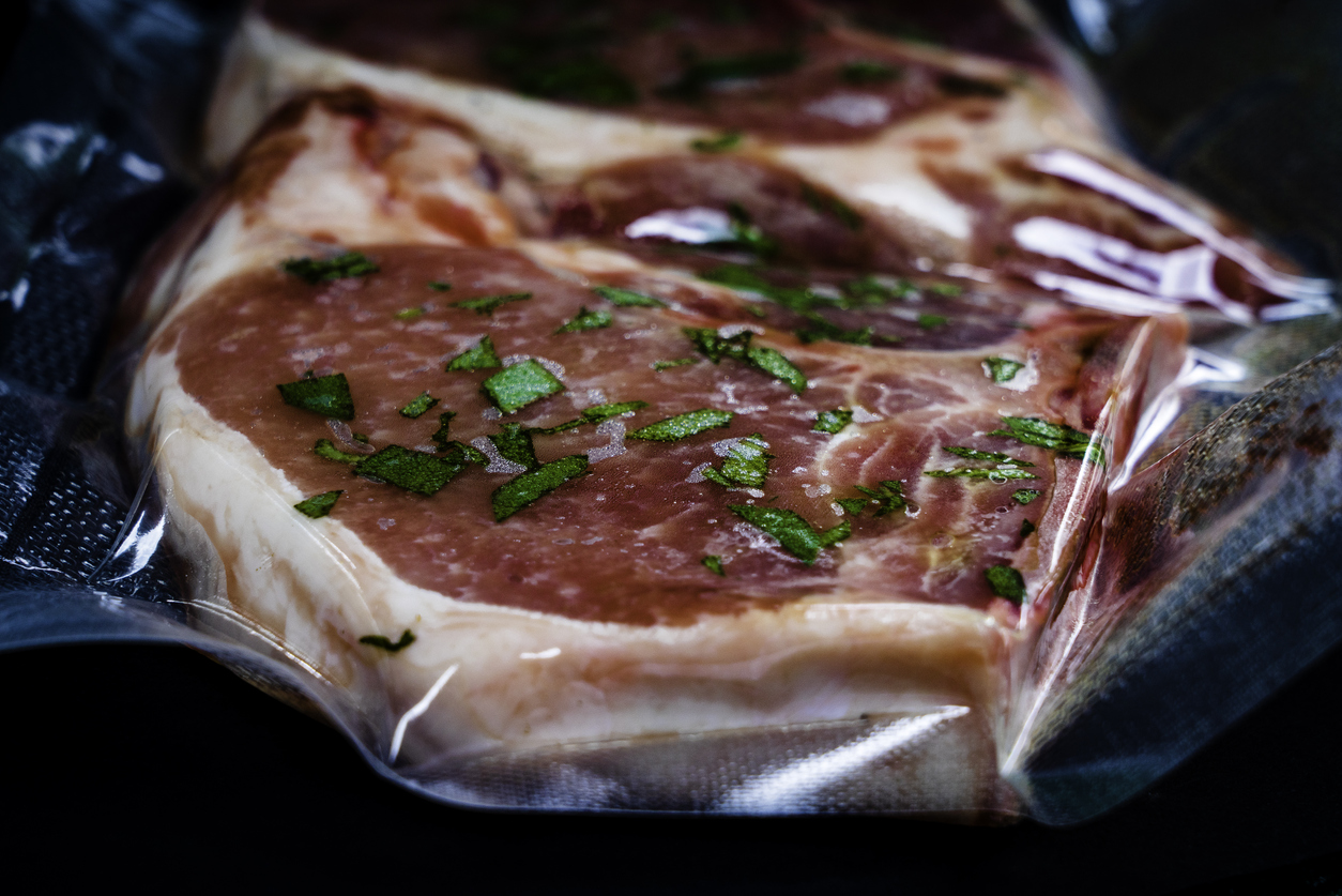 A steak with herbs inside a vacuum-sealed bag 