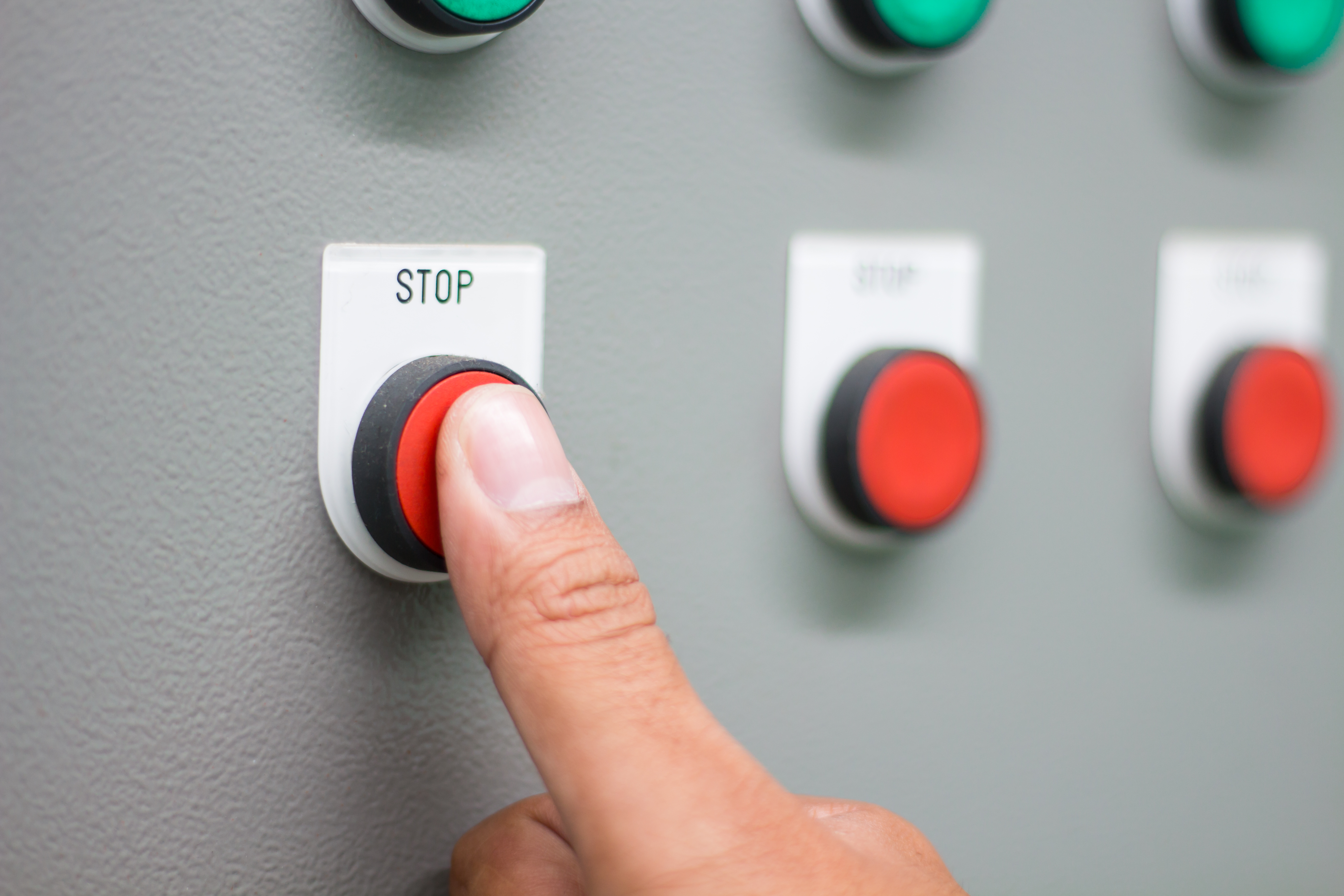 A person pressing a red stop button 