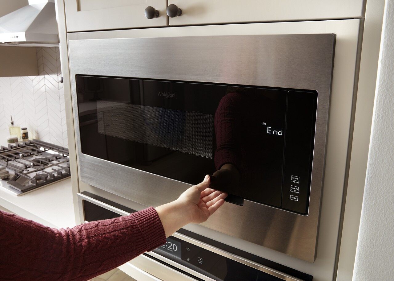 A person opening a Whirlpool built in microwave 