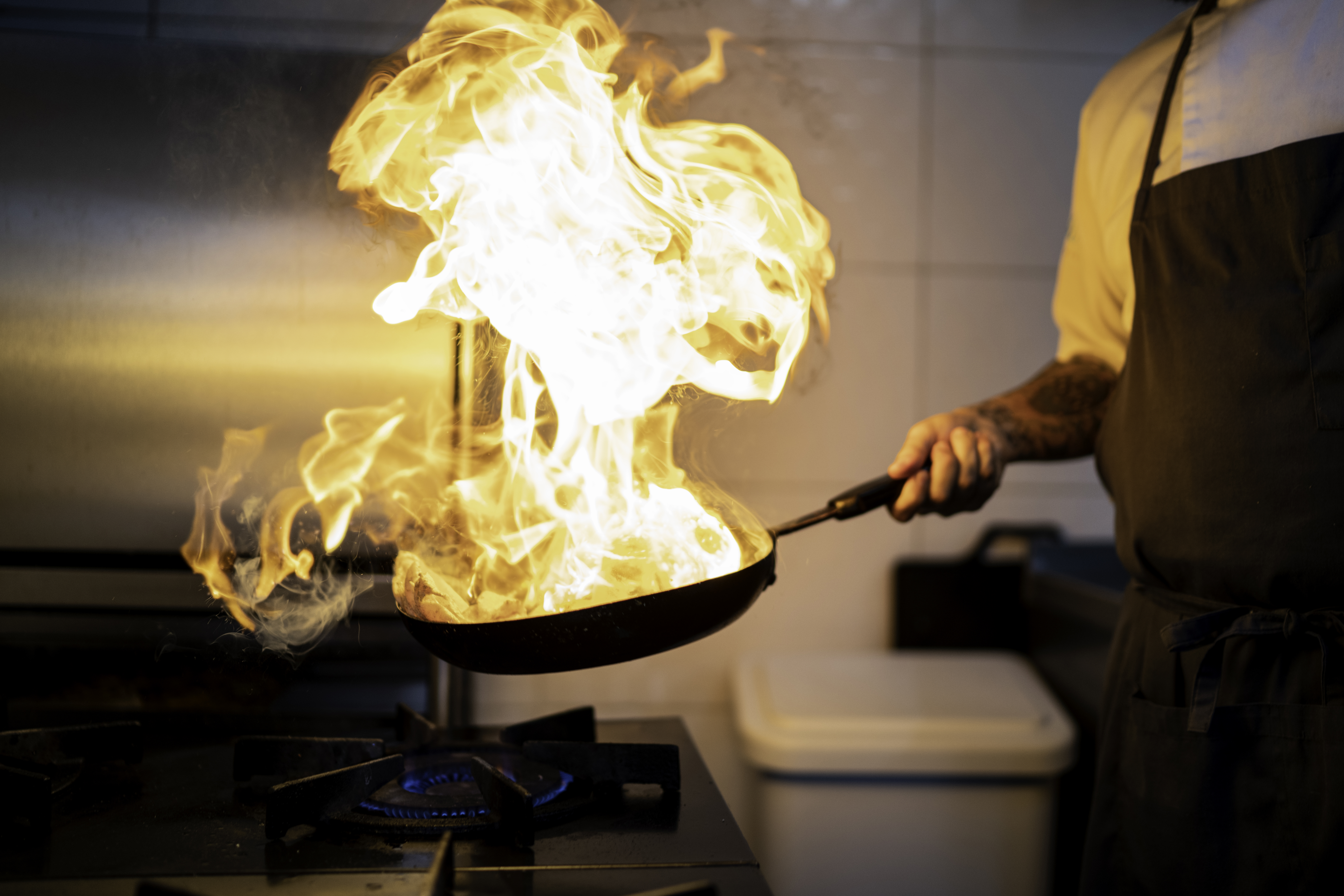 A chef cooking creating a flambe in a pan 