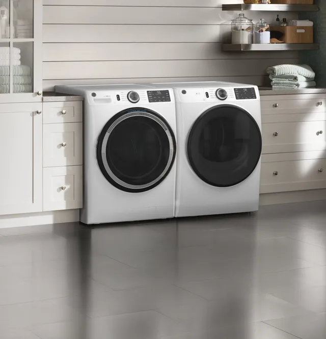 A matching front load GE washer and dryer in a laundry room 