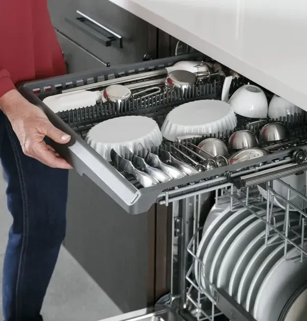 A woman pulling open the third rack on the GE Profile PDT715SYNFS dishwasher 