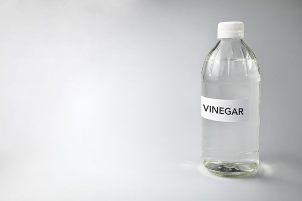 A bottle of white distilled vinegar against a white background