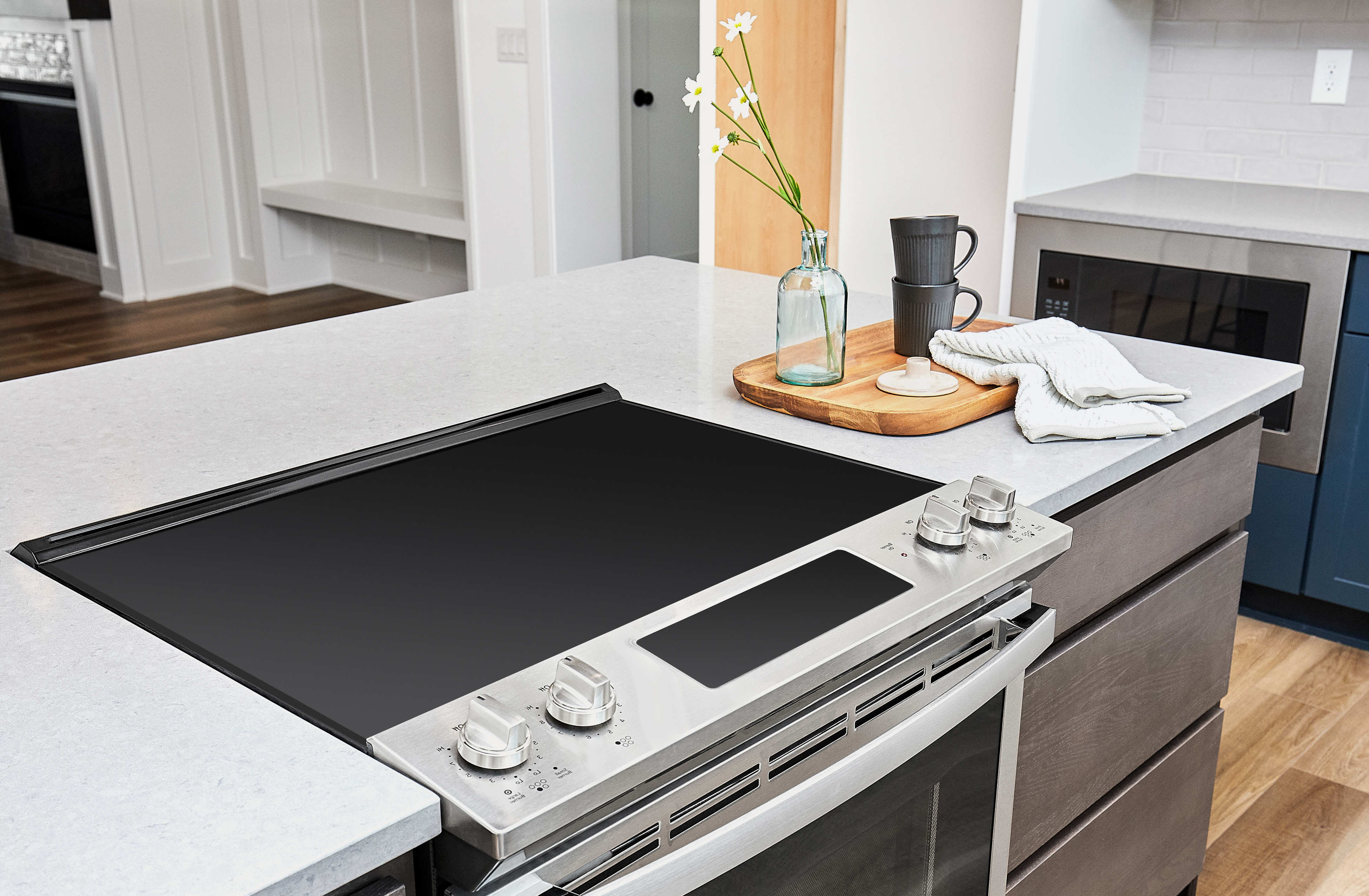 A slide in electric range installed in a kitchen island next to décor 