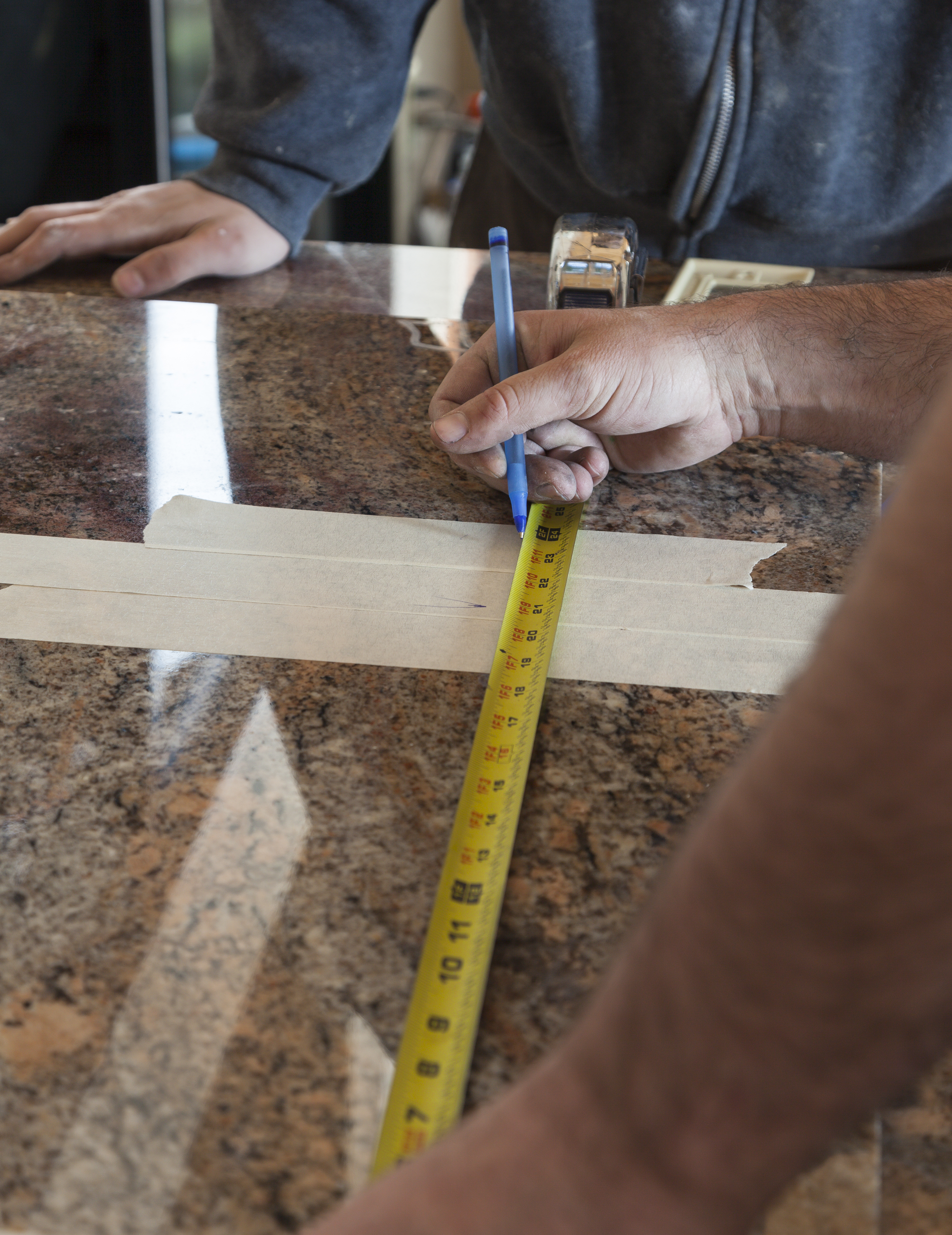 A person measuring a granite countertop