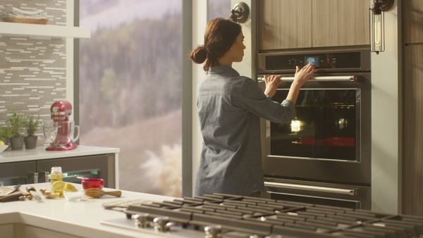 A woman using the KitchenAid KODE900HBS oven 