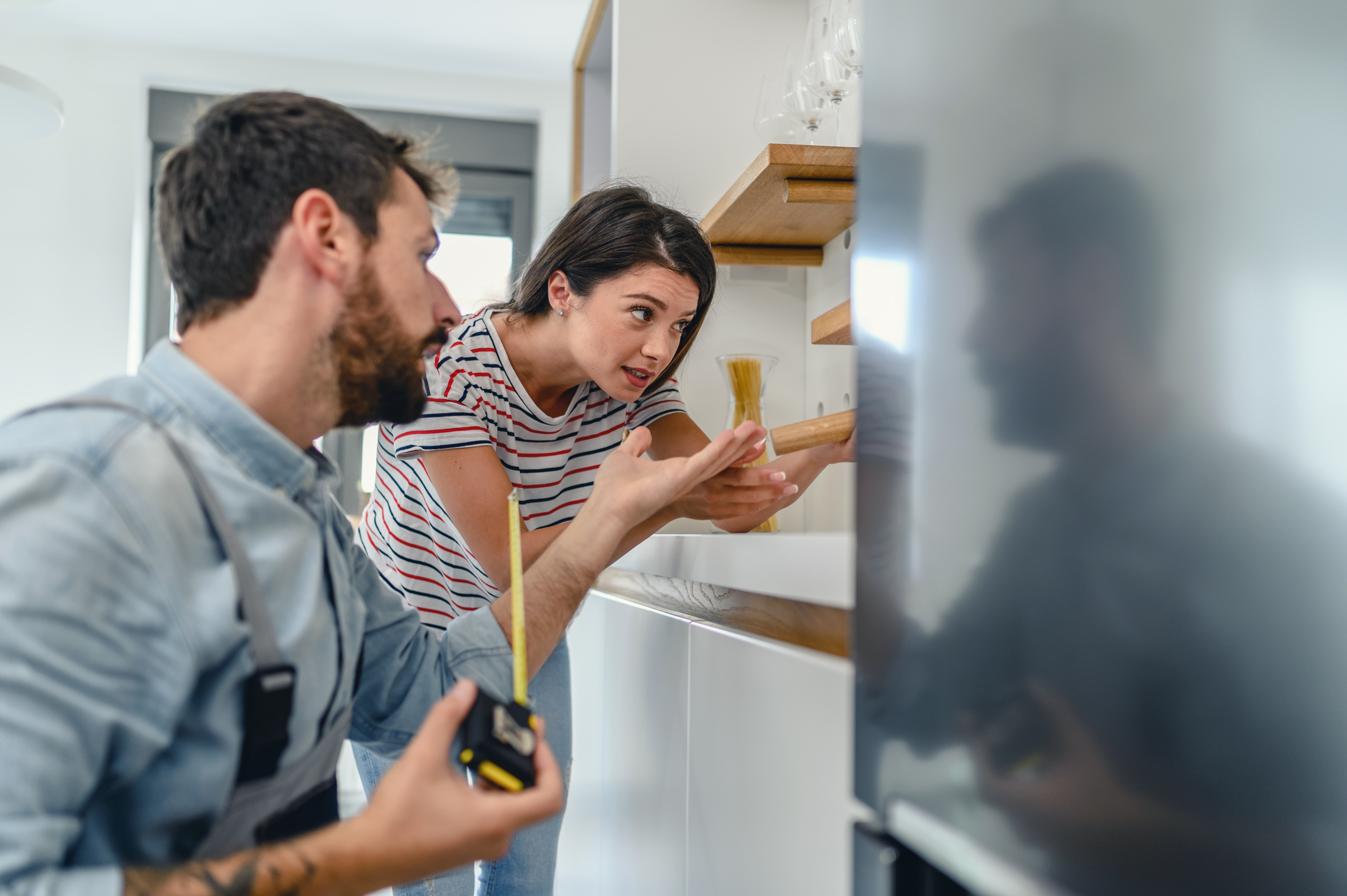 A man and woman measuring and balancing a refrigerator 