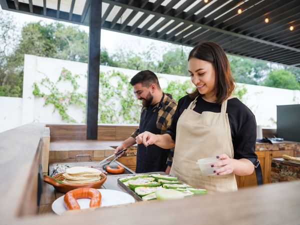  A man and a woman grilling in an outdoor kitchen 