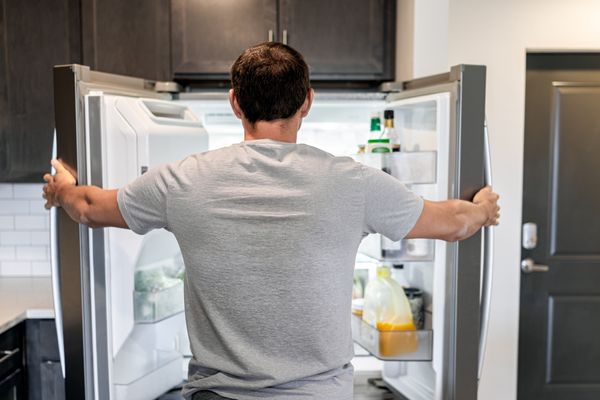 A man looking inside French door refrigerator 