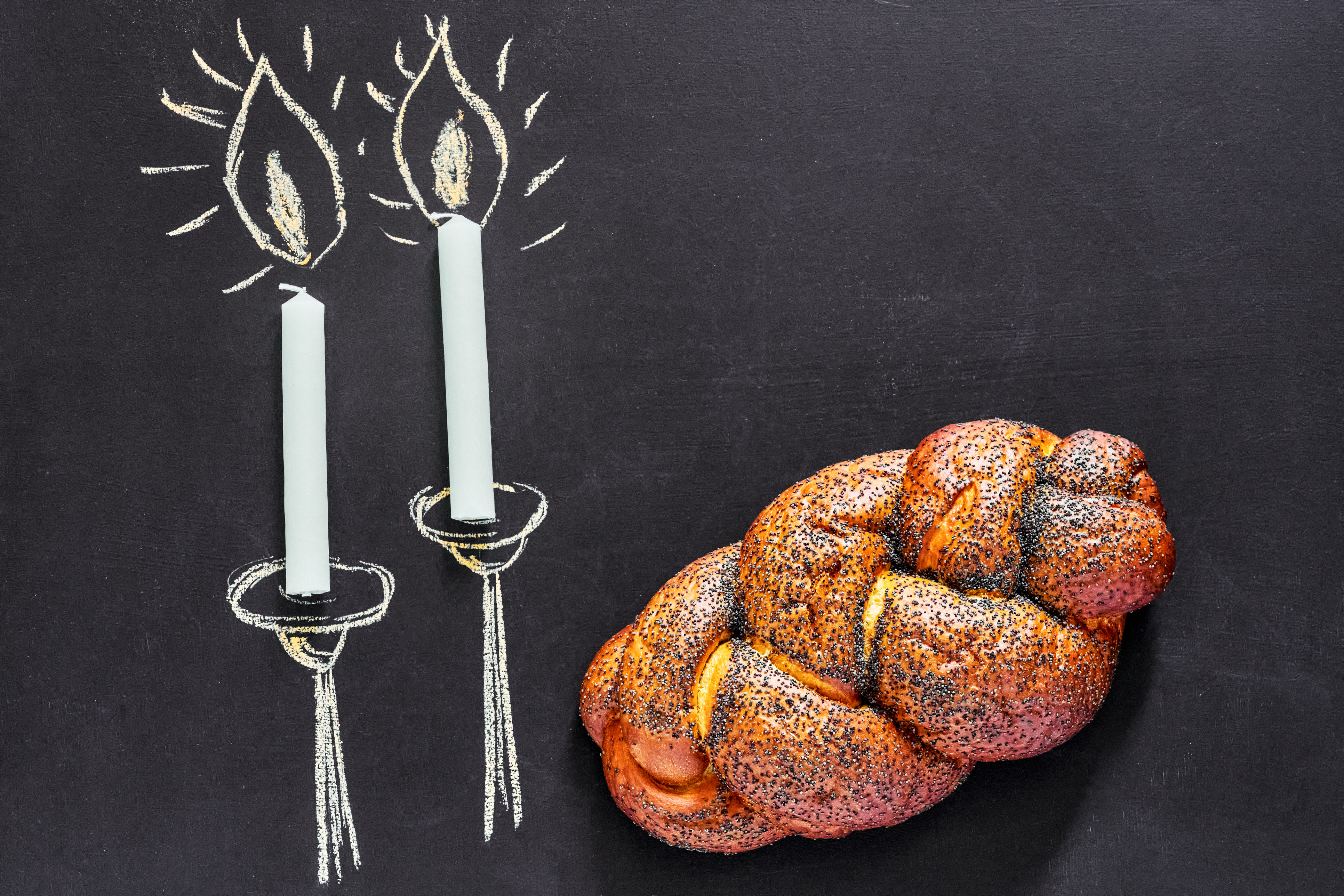 A loaf of bread next to a chalk drawing of Sabbath candles