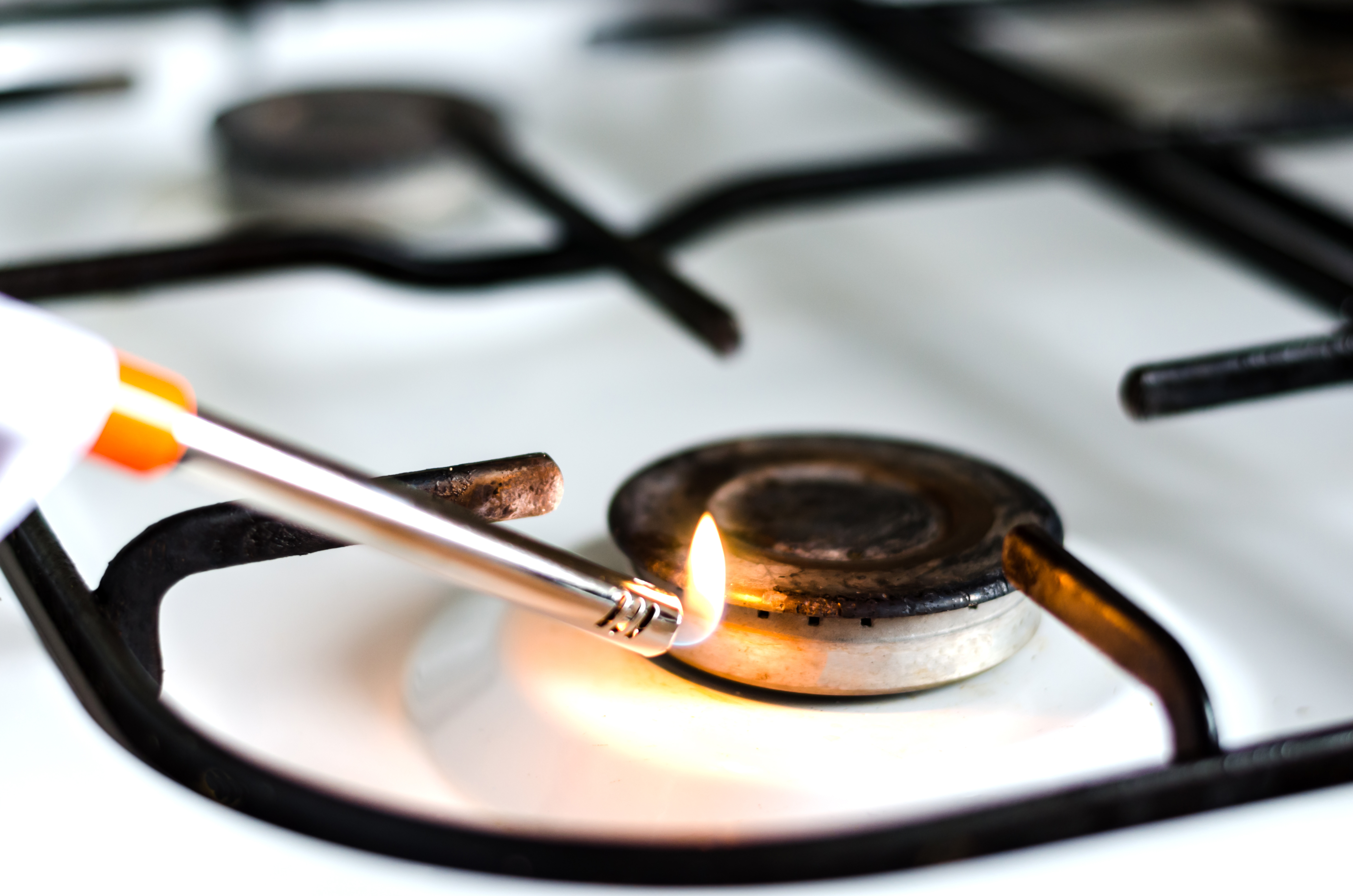 A person lighting a bad gas burner with a gas lighter 