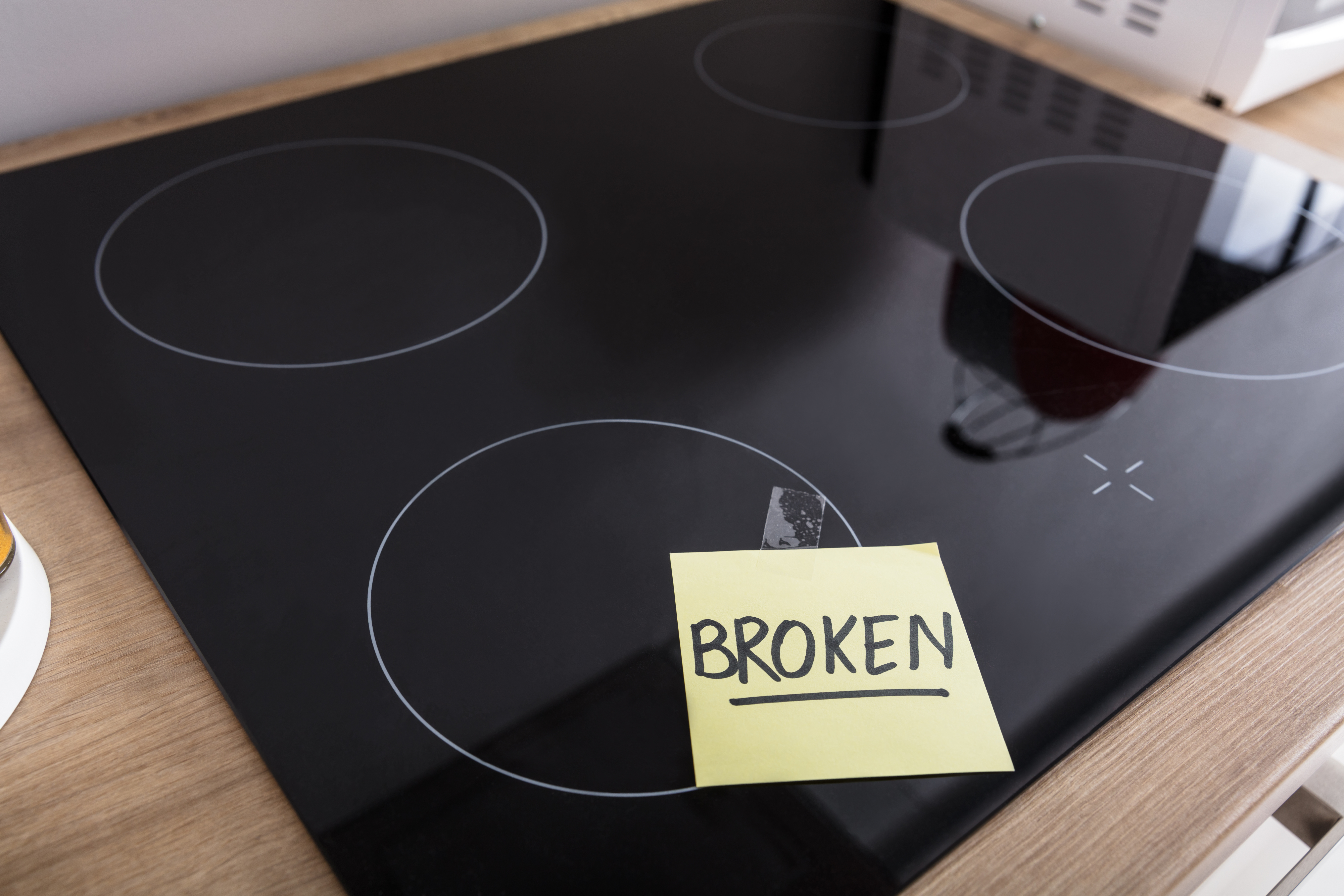A ceramic glass  cooktop with a sticky note that says BROKEN 