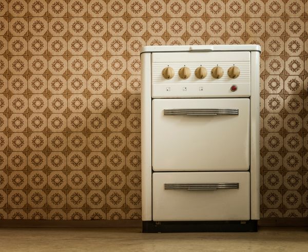 A vintage stove against a geometric tile wall  