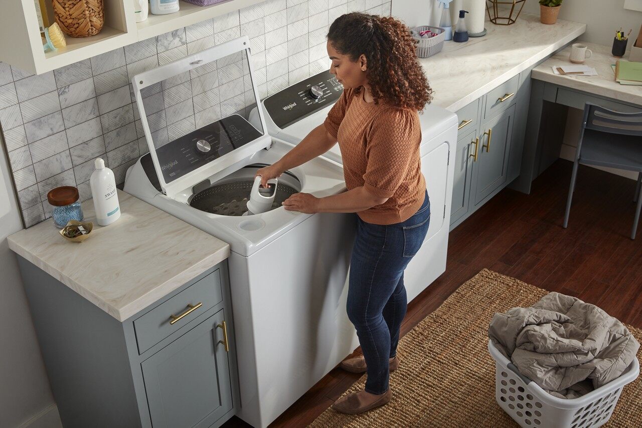 Woman adjusts agitator within a Whirlpool Top Load Washer