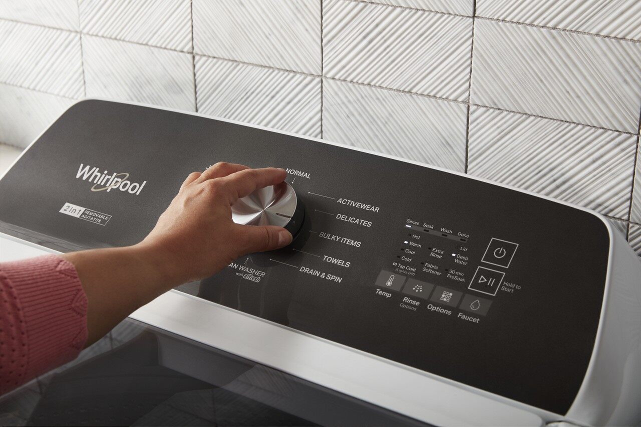 A person using the knobs on the Whirlpool WTW5057LW 2 in 1 top load washer 