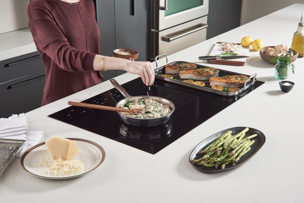 A woman cooking on a Wolf electric cooktop 