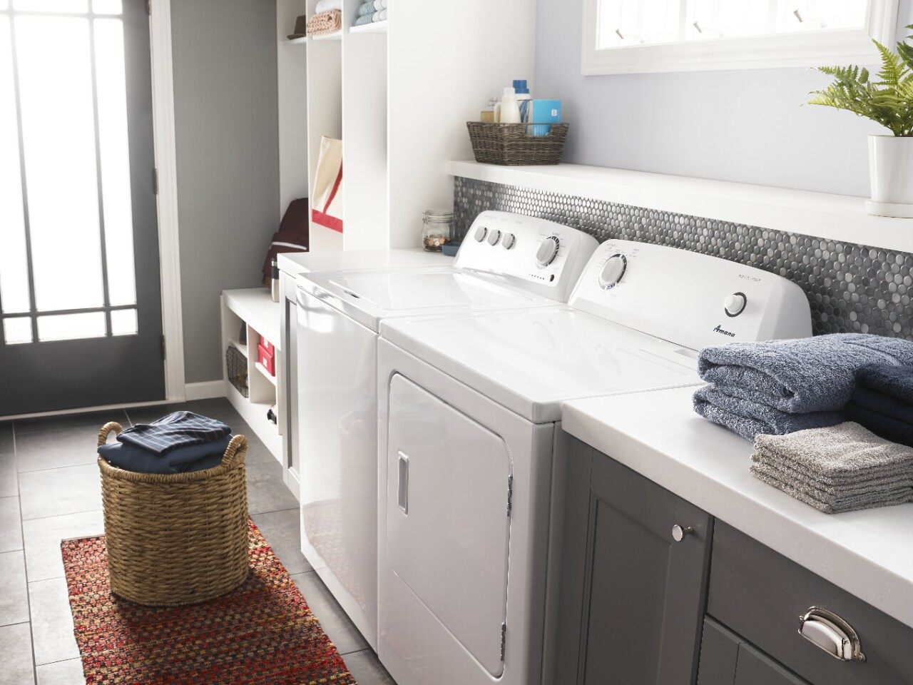 An Amana top load washer and matching dryer in a laundry room 