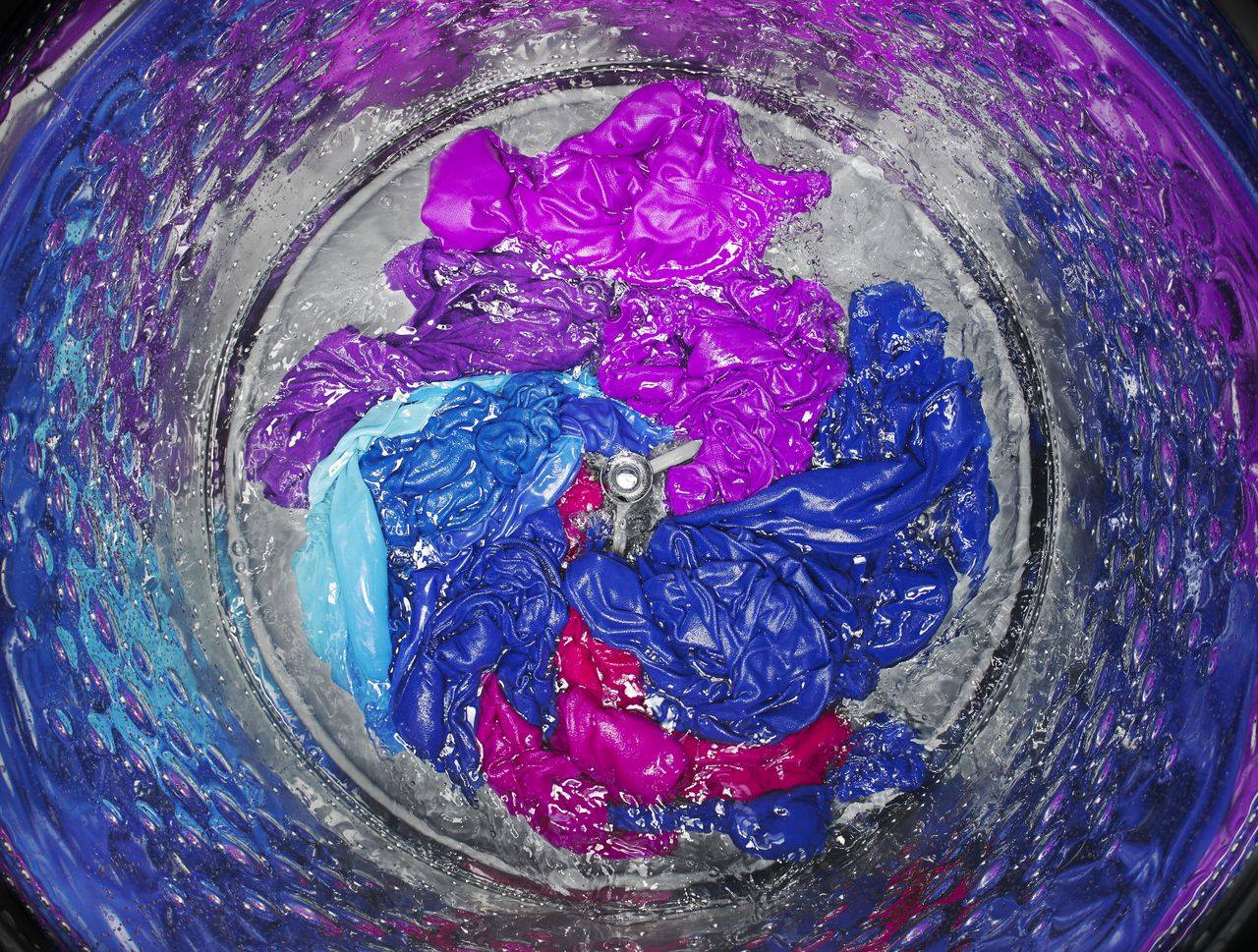 Purple and blue clothes washing inside a Whirlpool impeller washer 