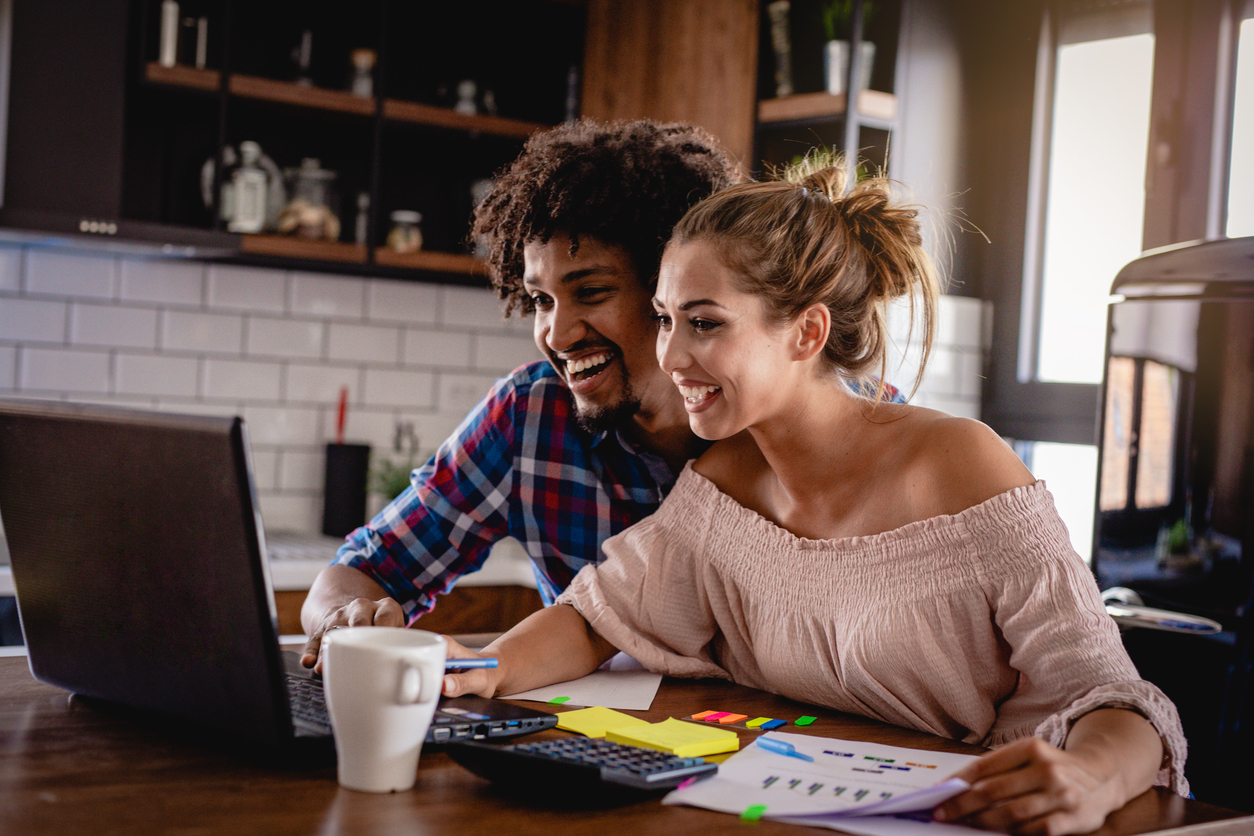 smiling young male and female couple doing research on a laptop 
