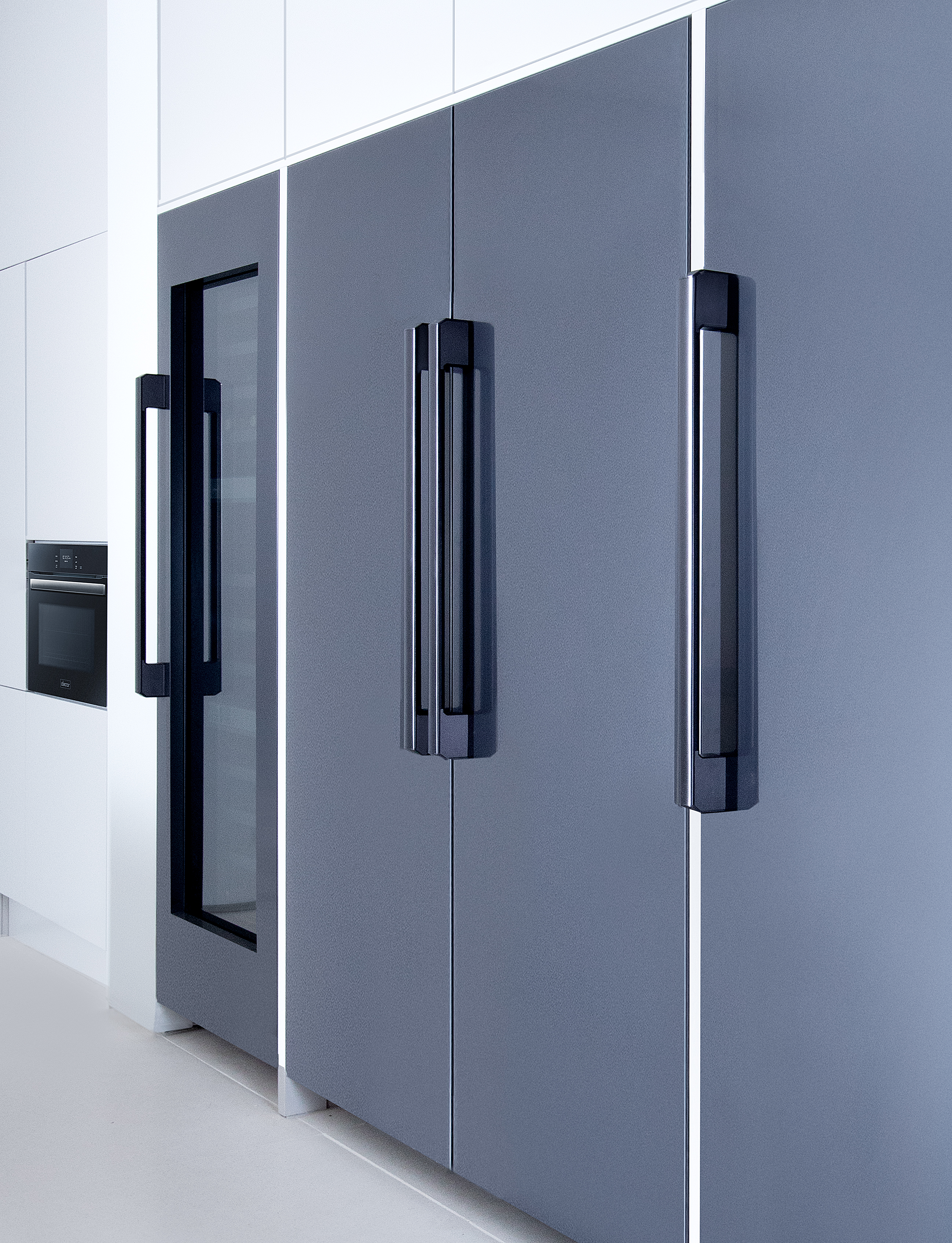 A side view of a Dacor column refrigerator, freezer, and wine refrigerator in a modern kitchen. 