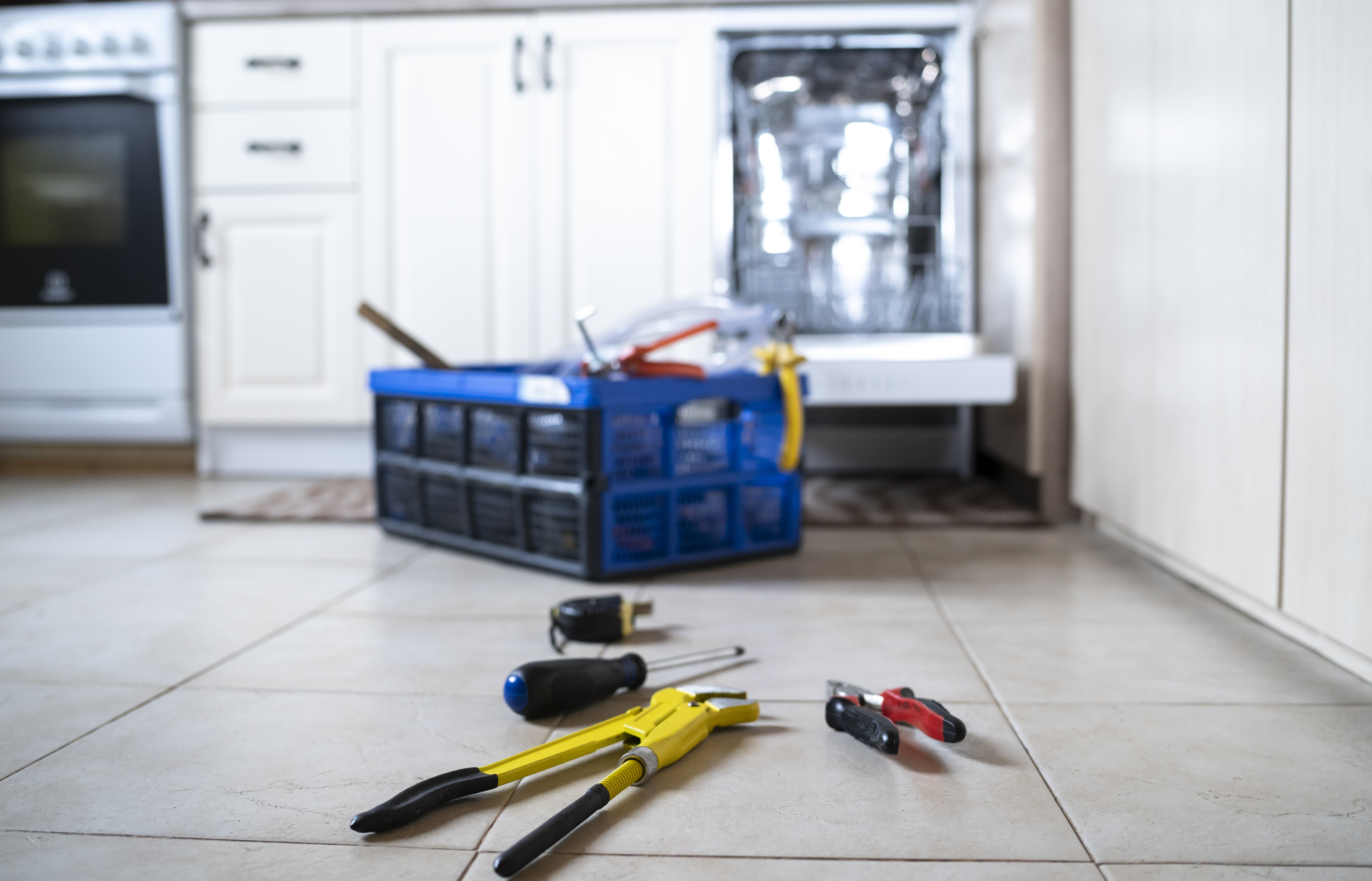 A toolbox in front of a dishwasher 