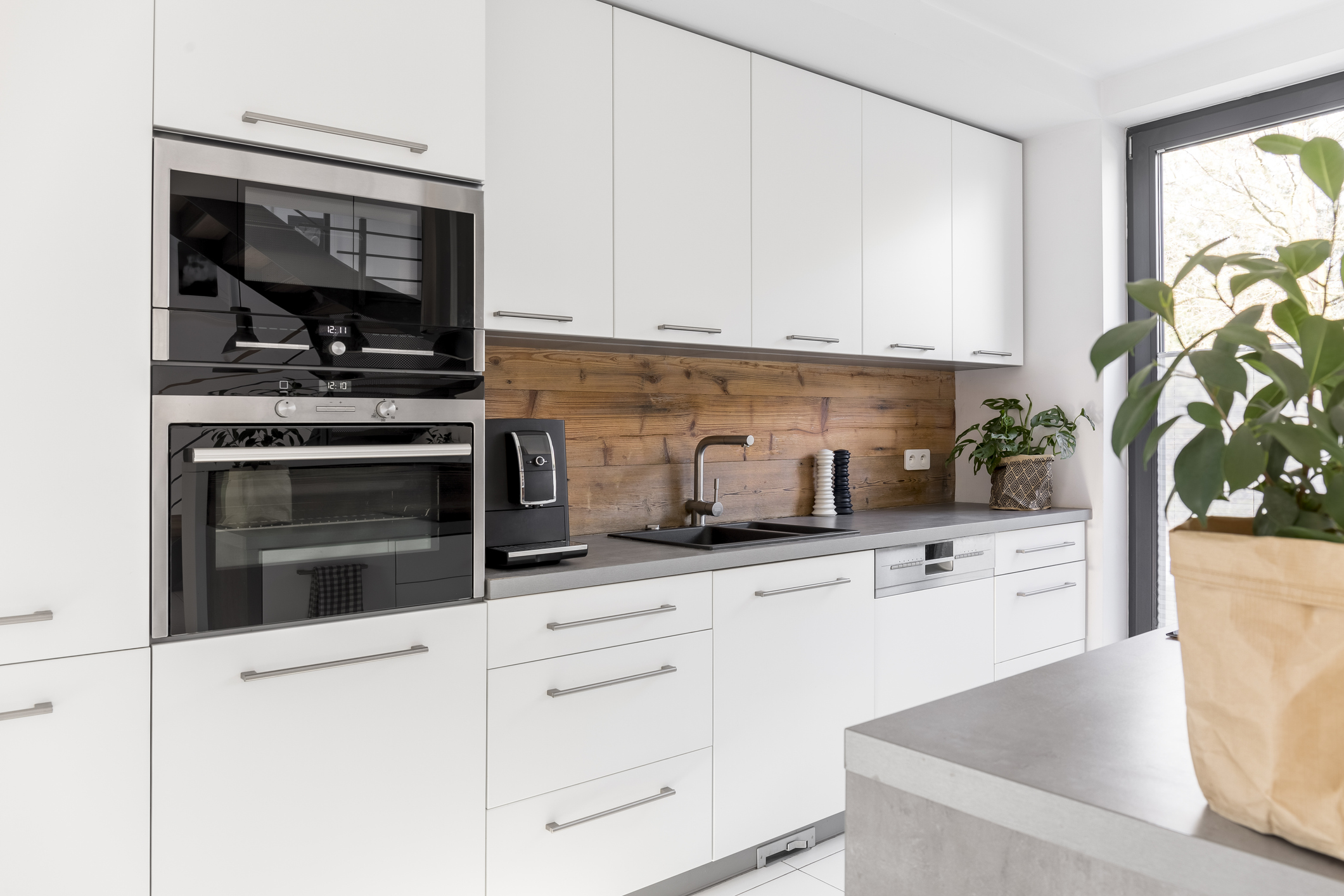 A wide shot of a white kitchen featuring a double wall oven 