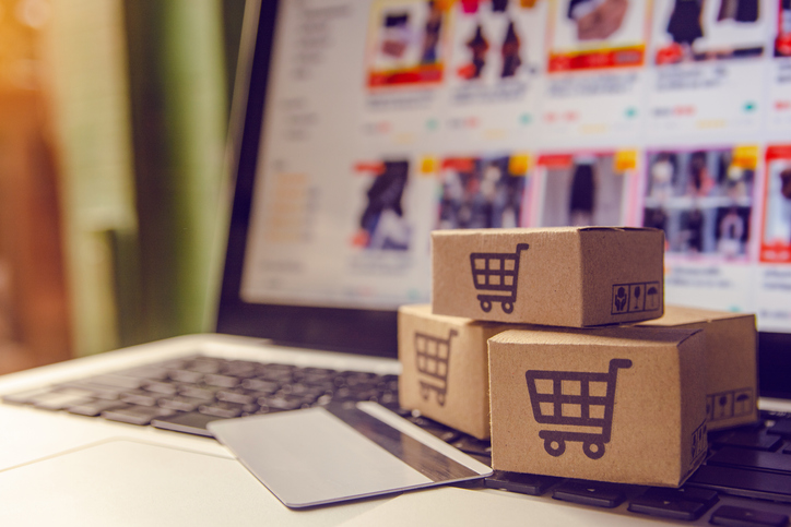 three mini boxes with e-cart logo staged next to a credit card with laptop in background