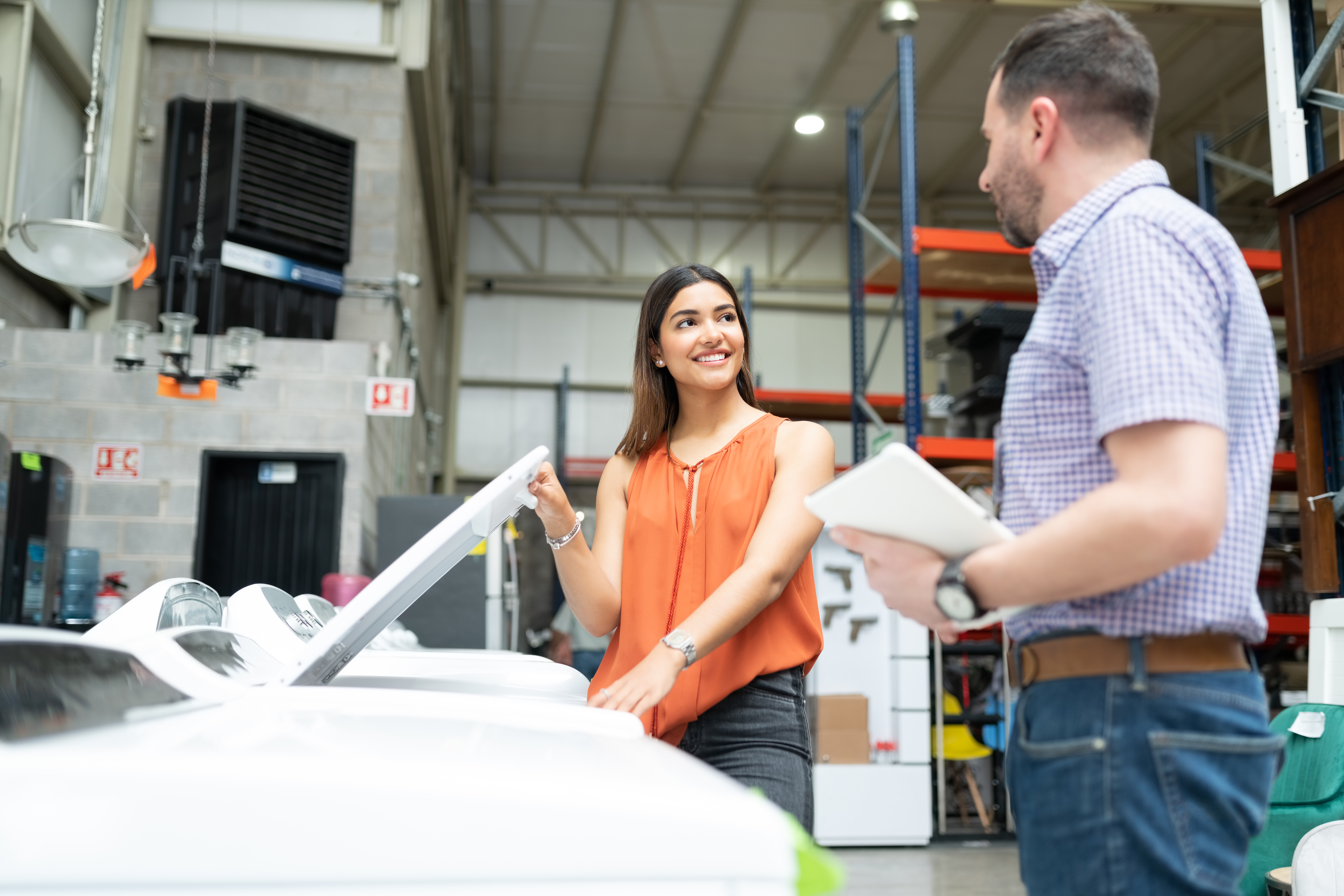 An appliance salesman with a clipboard talking to a woman smiling