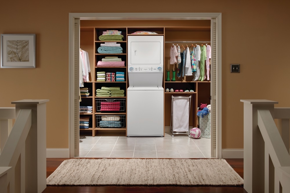 Wide shot of Frigidaire FLCG7522AW stacked washer dryer in a walk in closet