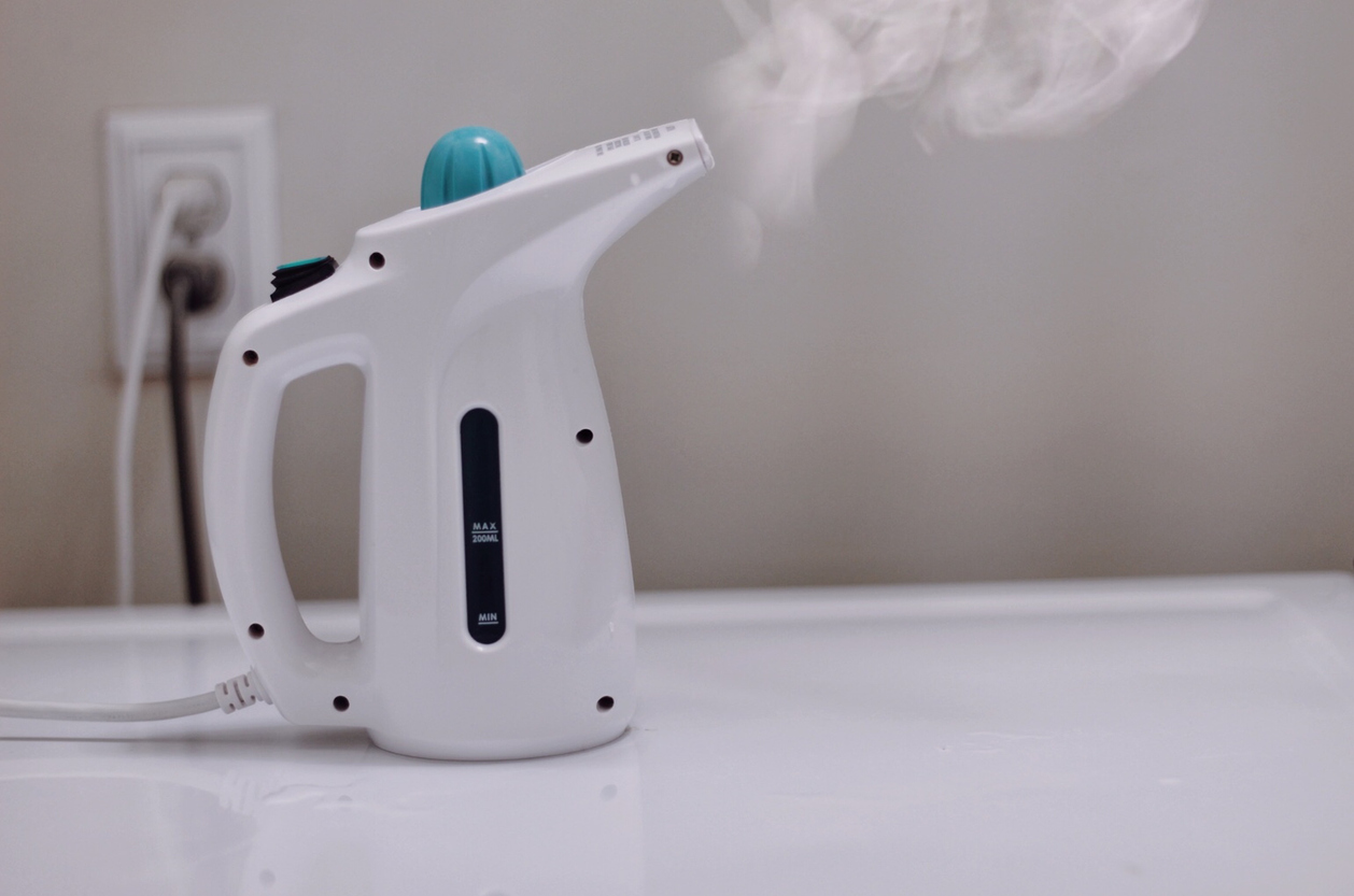garment steamer with steam shooting out of nozzle 