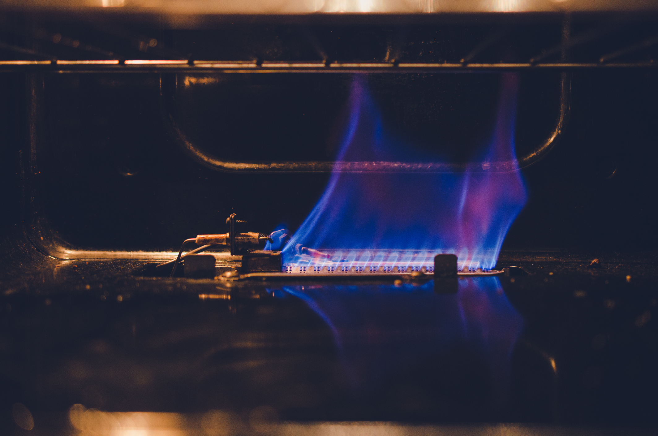 A close up of the pilot flame inside a gas oven 